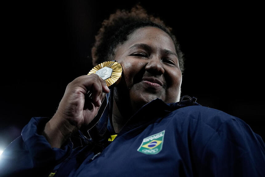 Beatriz Souza segurando a medalha próxima ao rosto na Olimpíada