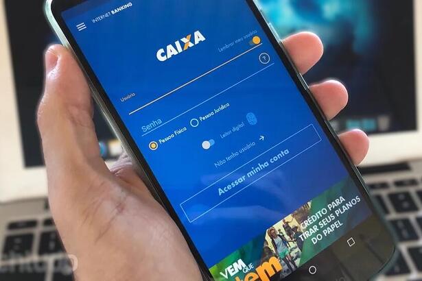 Homem segura o aplicativo da Caixa na mão