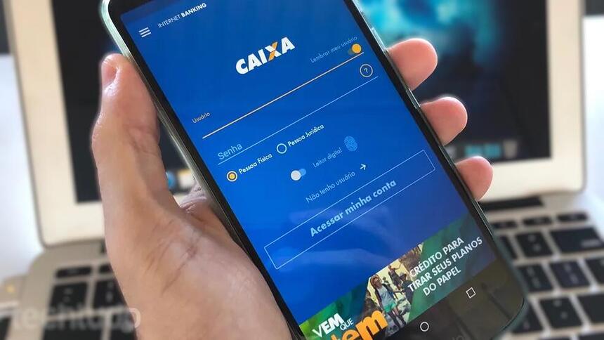 Homem segura o aplicativo da Caixa na mão