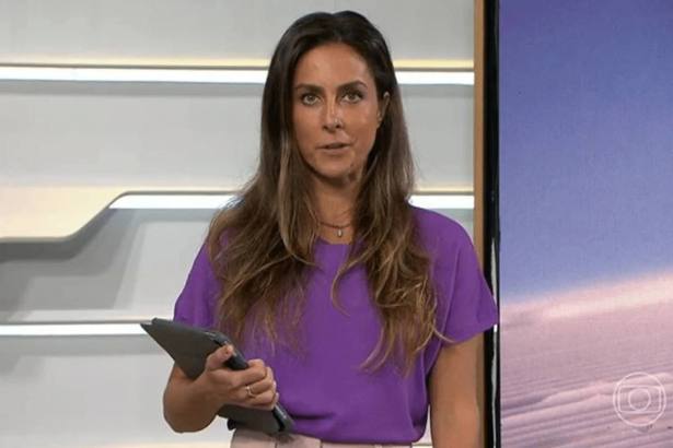 Carol Barcellos, com um tablet na mão, em pé no estúdio do Bom Dia Brasil