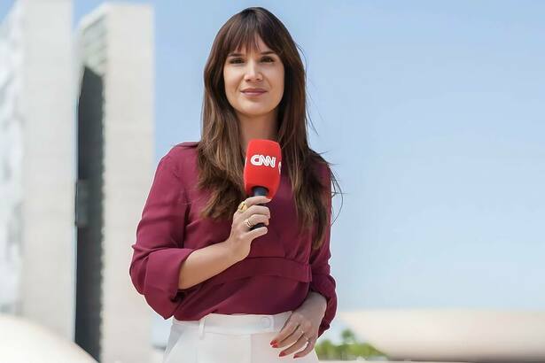 Renata Varandas segura microfone da CNN Brasil em frente a Câmara dos Deputados