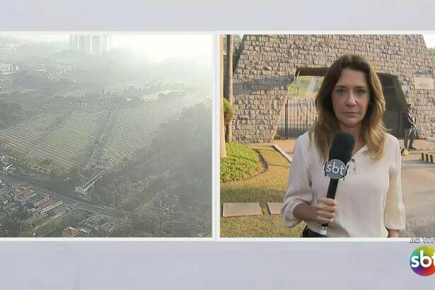 Repórter Flávia Travassos, do SBT, em frente ao cemitério onde Silvio Santos será enterrado. Imagens de helicóptero também dividem tela