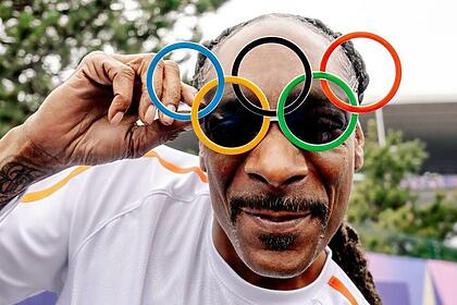 Snoop Dogg posando com um óculos com o arcos olímpicos na Olimpíada 2024