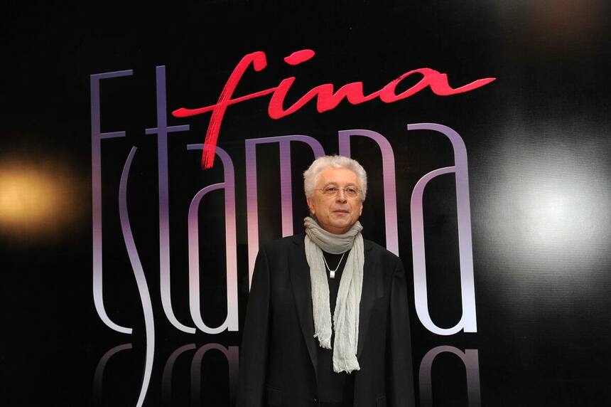 Aguinaldo Silva em frente a um banner com o logo da novela Fina Estampa, da TV Globo