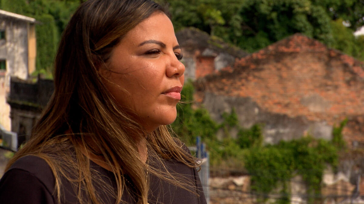 Mani Rego olhando para o morro em reportagem do Domingo RECORD