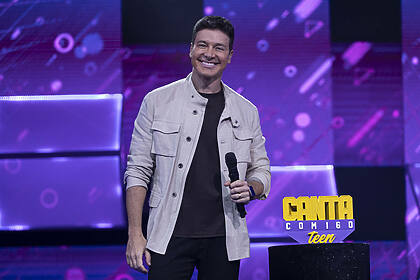 Rodrigo Faro sorrindo ao lado do troféu da final do Canta Comigo Teen