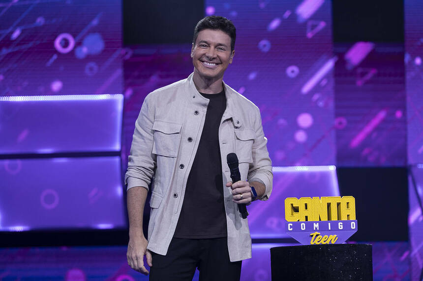 Rodrigo Faro sorrindo ao lado do troféu da final do Canta Comigo Teen