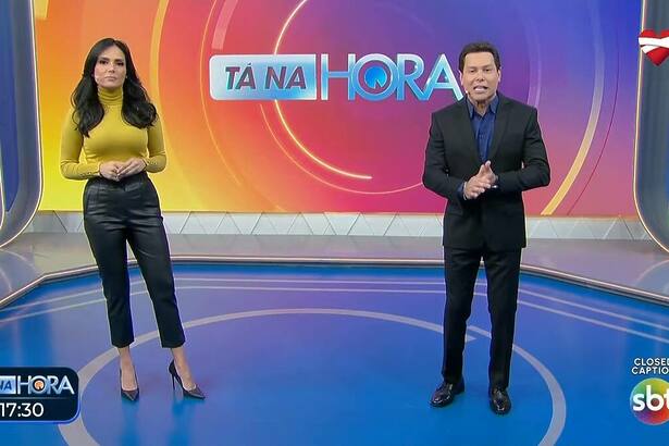 Marcia Dantas em pé ao lado de Marcão do Povo no centro do cenário do Tá na Hora no SBT