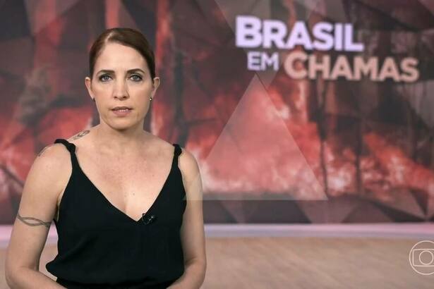 Poliana Abritta no cenário do Fantástico com o telão trazendo uma arte de queimadas e a chamada 'Brasil em Chamas'