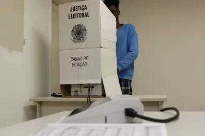 Homem votando em uma cabine de votação nas Eleições 2024