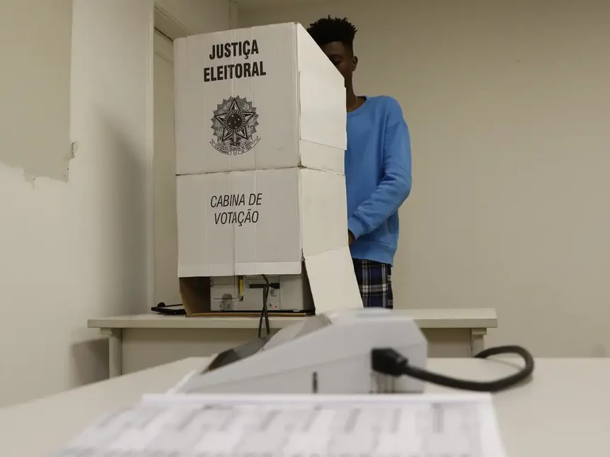 Homem votando em uma cabine de votação nas Eleições 2024