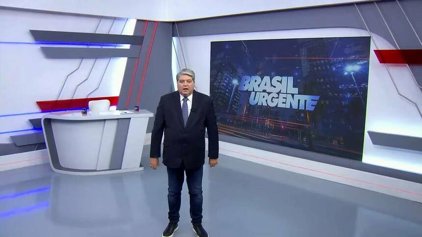 Datena no centro do cenário do Brasil Urgente com terno e gravata