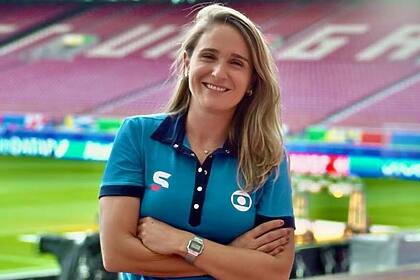 Julia Guimarães posando em um estádio de futebol com uniforme de esporte da Globo