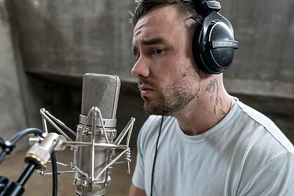 Liam Payne com semblante triste em frente a um microfone