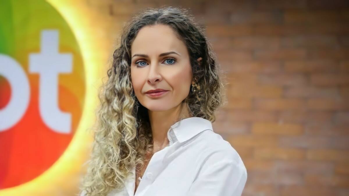 Luciana Valério com blusa branca em frente ao logo do SBT