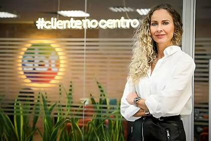 Luciana Valério, sorrindo, em frente ao logo do SBT