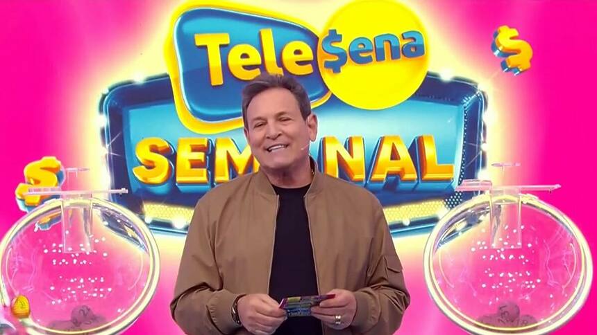 Luiz Ricardo Sorrindo no cenário da Tele Sena Semanal, edição 22, que está na cor rosa