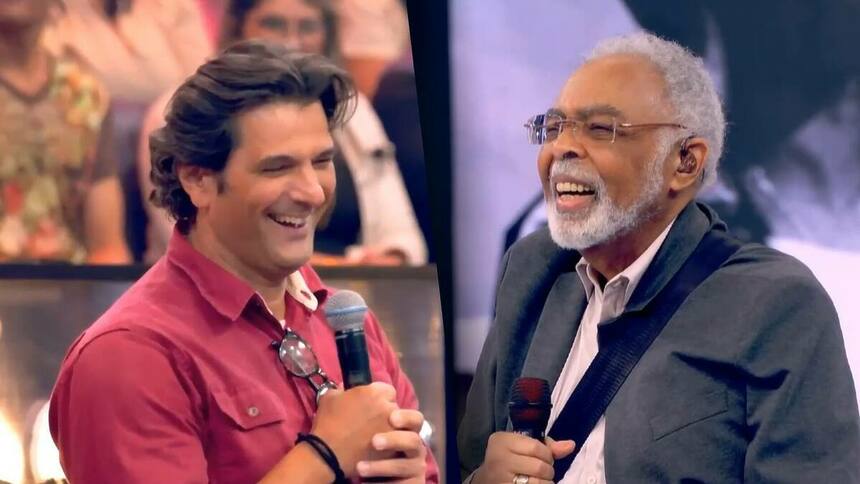 Ator Gilberto Gil de frente a cantor Gilberto Gil no Caldeirão. Os dois estão sorrindo