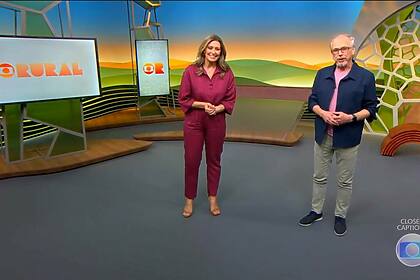 Cristina Vieira de roupa vermelha e Nélson Araújo com camisa de manga azul e camisa por dentro rosa, no cenário do Globo Rural, sorridentes