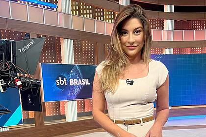 Kallyna Sabino no centro do cenário do SBT Brasil sorrindo par a câmera