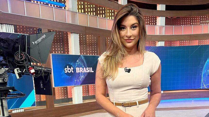 Kallyna Sabino no centro do cenário do SBT Brasil sorrindo par a câmera