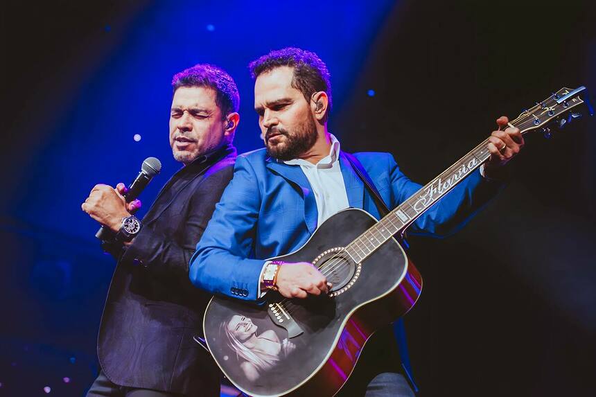 Zezé Di Camargo e Luciano cantando juntos. Luciano toca um vilão preto