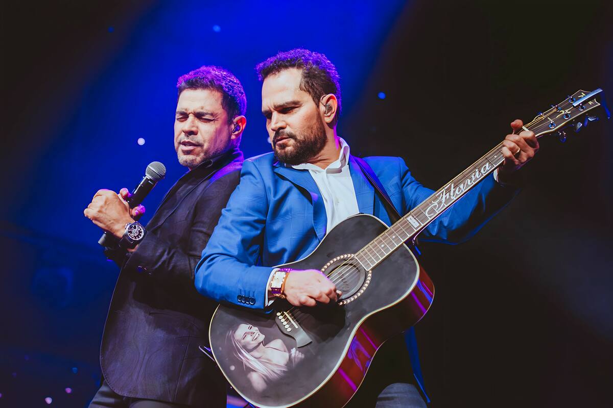 Zezé Di Camargo e Luciano cantando juntos. Luciano toca um vilão preto