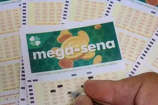 Uma mão preenchendo uma cartela de sorteio da Mega-Sena