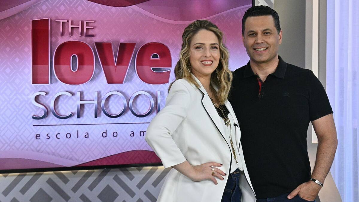 Renato e Cristiane Cardoso, em foto posada, juntos e abraçados na frente do telão do The Love School