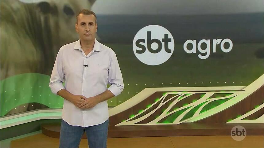 Sandro Ivanowski de camisa branca na frente do logo do SBT Agro no telão do SBT