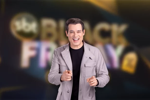 Celso Portiolli sorrindo na frente do logo SBT Black Friday