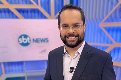 Marcelo Casagrande sorrindo no cenário do SBT News na TV