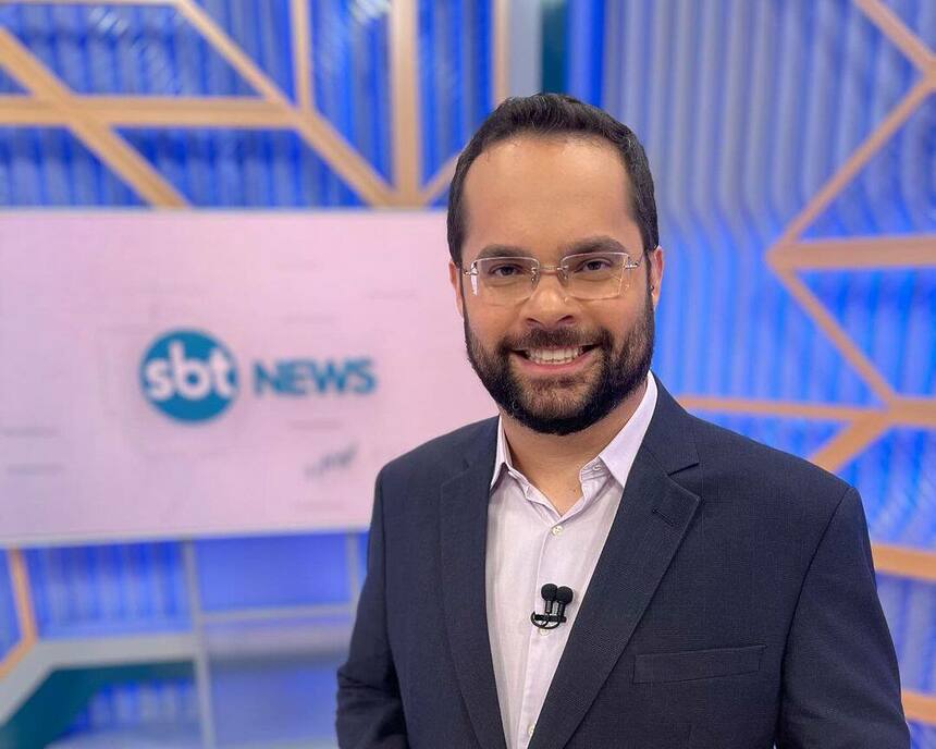 Marcelo Casagrande sorrindo no cenário do SBT News na TV