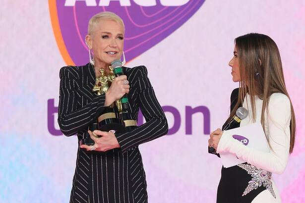 Xuxa segura os três prêmios do Troféu Imprensa no palco do Teleton 2024