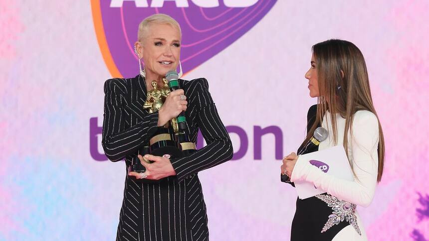 Xuxa segura os três prêmios do Troféu Imprensa no palco do Teleton 2024