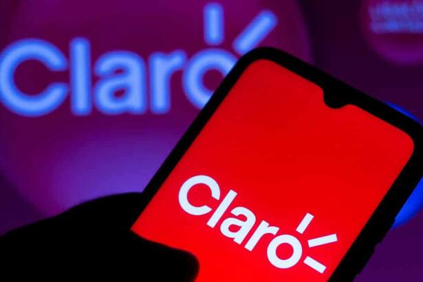 Mão segura telefone que mostra o logo da Claro