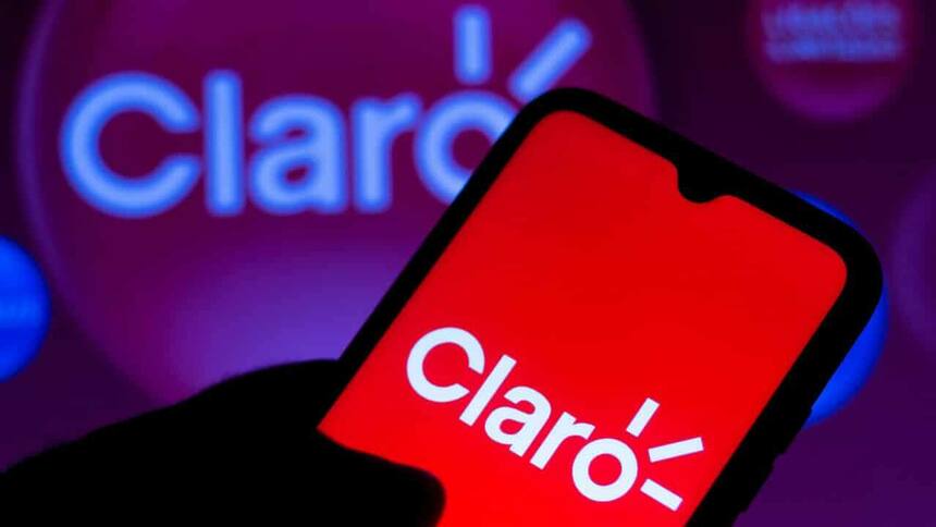 Mão segura telefone que mostra o logo da Claro