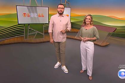 Pedro Málaga ao lado de Helen Martins no cenário do Globo Rural eles vestem roupas em tom rosa e marrom