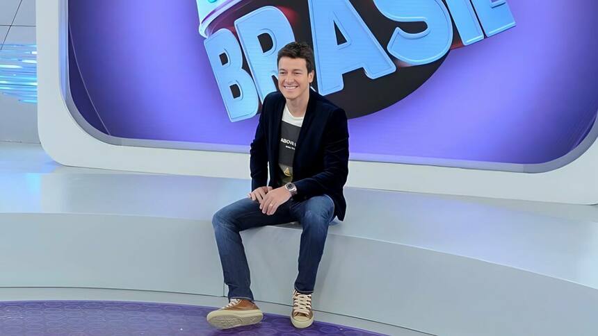 Rodrigo Faro sentado no palco do programa Melhor do Brasil, da RECORD. Ele está sorrindo