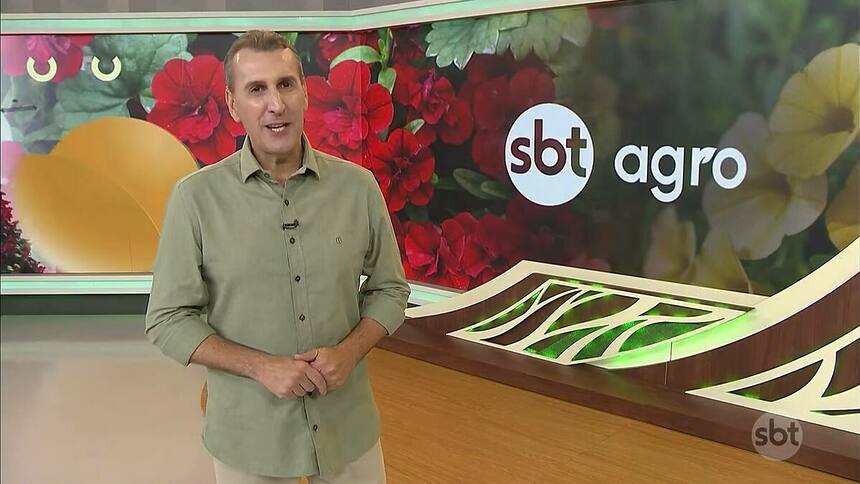 Sandro Ivanowski em frente ao logo do SBT Agro no estúdio da emissora