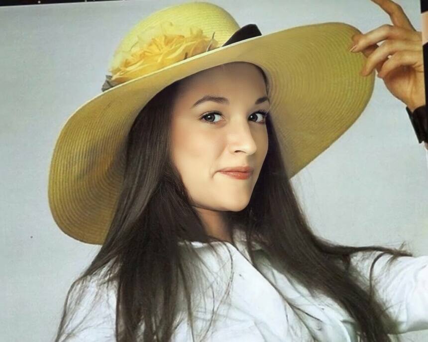 Olivia Hussey segura chapéu amarelo na cabeça e sorrir