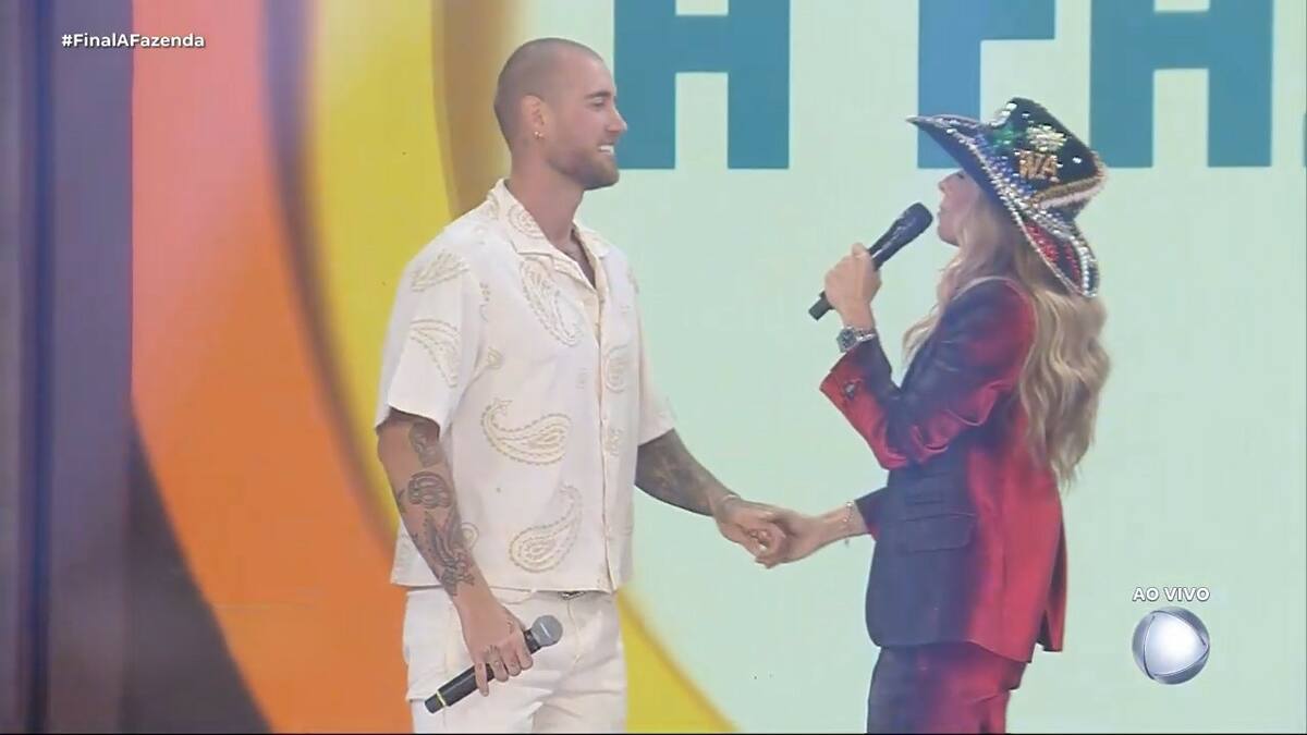 Adriane Galisteu segura nas mãos de Yuri Bonotto no palco da Final de A Fazenda 16