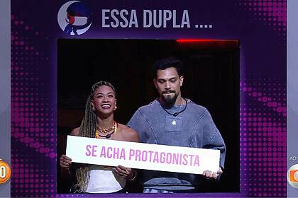 Aline e Vinicius segurando a placa "Se acham protagonistas" em trecho do Sincerão no BBB 25