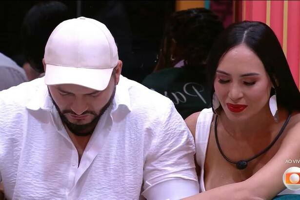 Marcelo com a cabeça baixa de boné branco e Arleane olhando para o chão no BBB 25