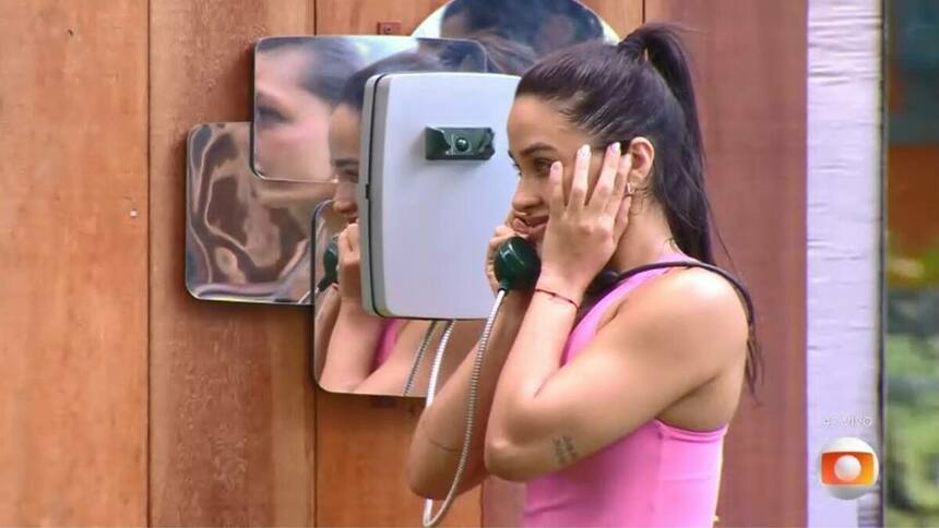 Eva, com a mão no ouvido, ao atender o Big Fone no BBB 25