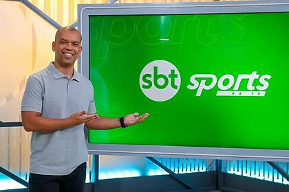 Narrador Luiz Alano apontando pro telão no cenário do SBT Sports