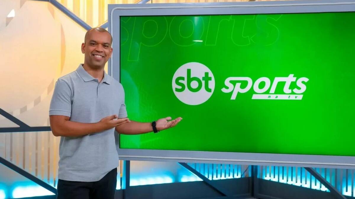 Narrador Luiz Alano apontando pro telão no cenário do SBT Sports