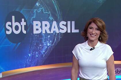 Simone Queiroz de blusa branca e sorridente apresentando o SBT Brasil