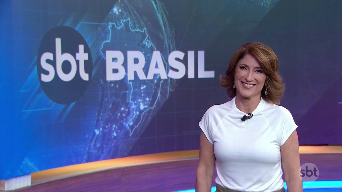 Simone Queiroz de blusa branca e sorridente apresentando o SBT Brasil