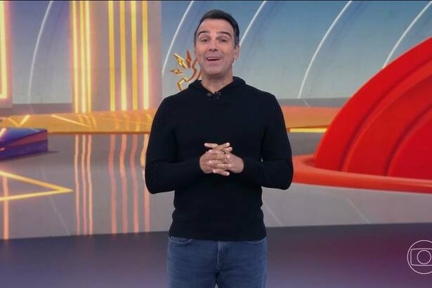 Tadeu Schmidt veste preto no centro do cenário do BBB 25